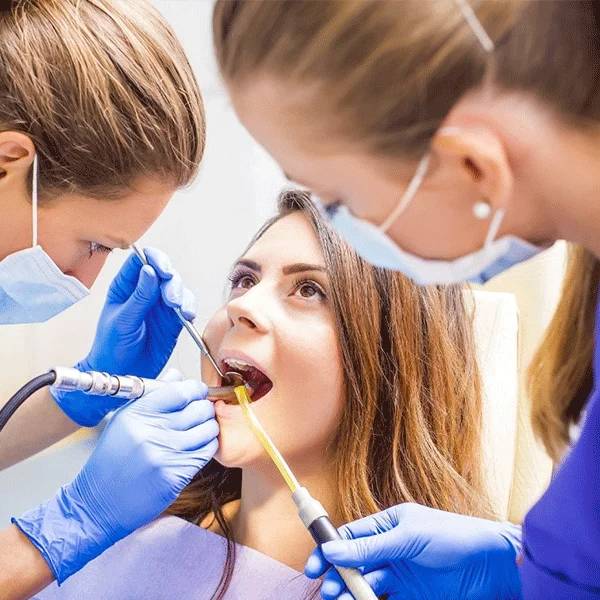 Dental professionals examining a patient's teeth in a clinical setting